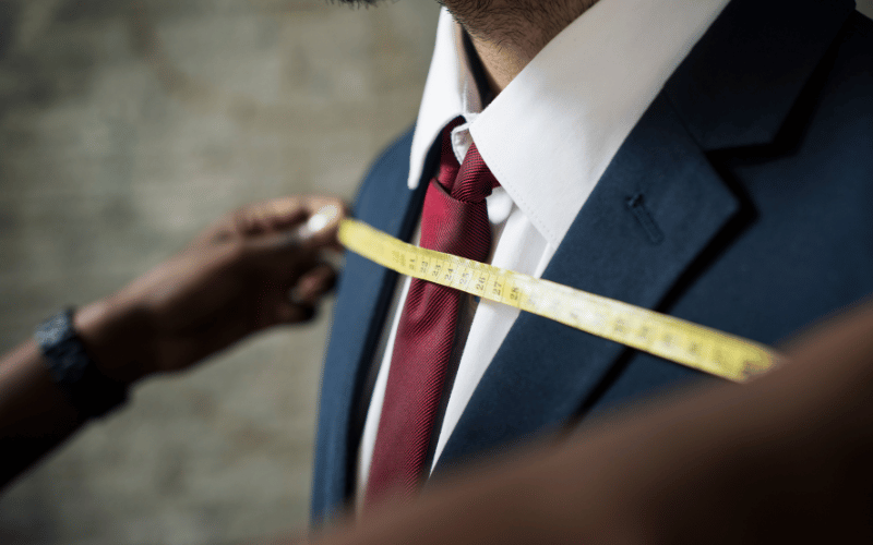 Tailor taking measurements of suit jacket