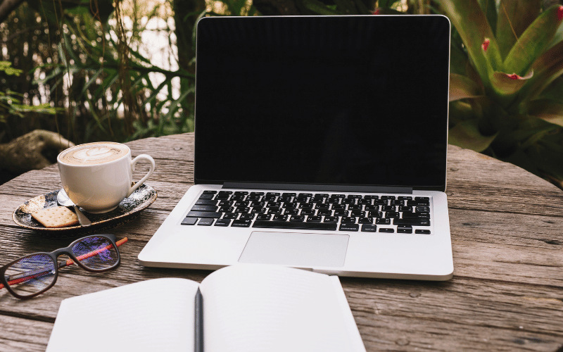 Accountants laptop outside on a table with coffee and glasses